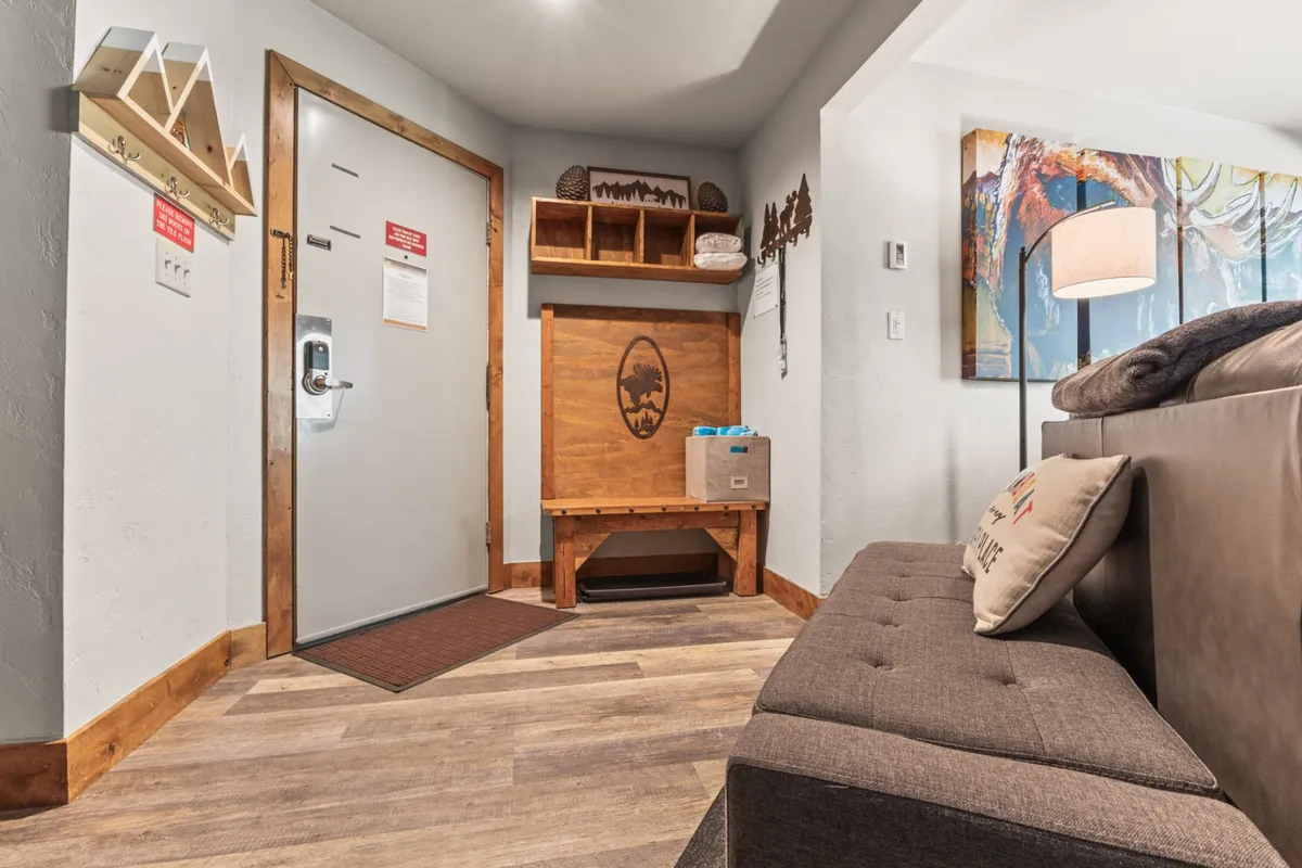 A practical entryway area featuring a bench, shelves, a lamp, and artistic touches—ideal for storing outdoor gear and creating a warm welcome. The setup is perfect for transitioning from outdoor adventures to indoor comfort, echoing the mudroom described in the section.